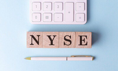 NYSE on wooden cubes with pen and calculator, financial concept