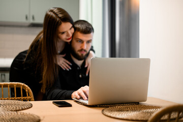Young woman and a man with are sitting at the table with a laptop