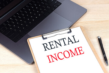 RENTAL INCOME text written on a paper clipboard on laptop