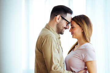 Beautiful couple hugging and looking at each other. Close-up portrait of a caucasian young loving couple embracing. Happy millennial husband and wife hug cuddle enjoy tender romantic moment