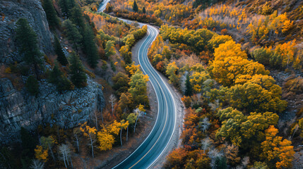 A mountain road with minimal traffic surrounded by autumn foliage midday.