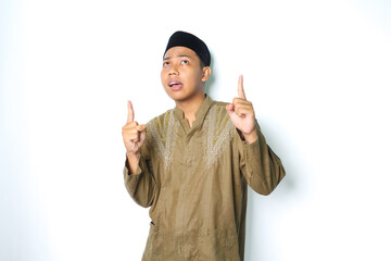 confused asian muslim man pointing to above looking up wearing koko clothes isolated on white...