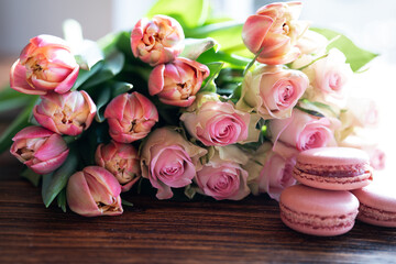 Beautiful pink bouquet of flowers and fine delicacies on dark wood. Sweet pastries with roses and...