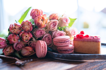 Beautiful pink bouquet of flowers and fine delicacies. Sweet pastries with roses and tulips against...