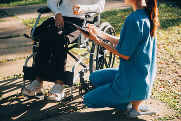 Nursing staff talking to an elderly person sitting in a wheelchair. - obrazy, fototapety, plakaty