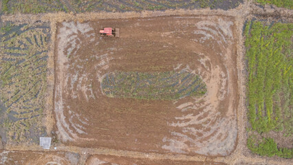 Aerial view of farmers plowing rice fields using a machine
