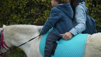 4-Year-Old Boy on Pony Ride, Supported by Mother