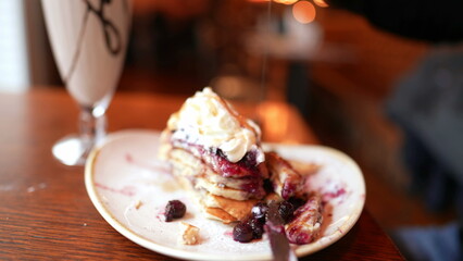 Adding honey on top of dessert at restaurant, sugar plate of pancake with chantilly and milkshake