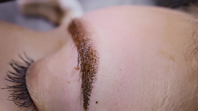 Macro shot of permanent makeup where the needle from the cartridge introduces pigment into the skin of the eyebrows. Permanent makeup procedure, performing PMU of eyebrows