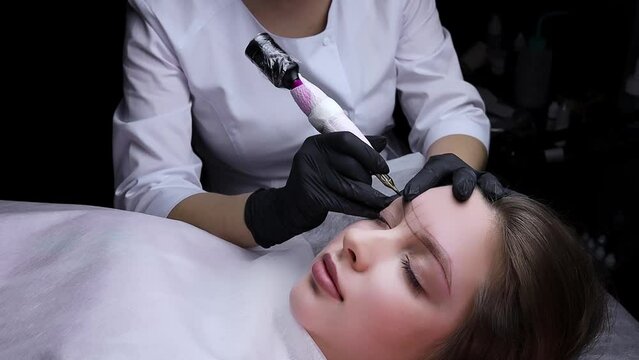 The master of permanent makeup performs the procedure permanent eyebrow makeup. Permanent makeup procedure, performing PMU of eyebrows
