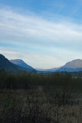 A tranquil landscape featuring a view of mountains under a soft blue sky.