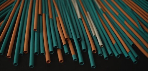  a group of blue and orange pipes laying on top of a black table next to a pile of orange and white straws on top of a black table top.