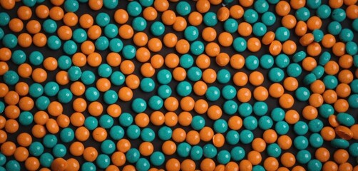  a bunch of orange and blue candies are arranged in a pattern on top of each other on a black surface with orange and blue candies on top of the candies.