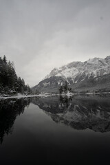 A serene winter scene with snow-covered mountains reflected on a still lake.