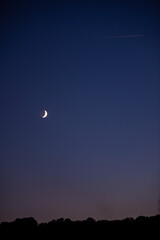 Natural satellite of the earth. Young crescent moon on a clear sky at the end of the day in the summer