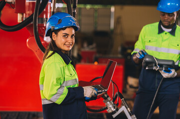 Female engineers work as a team training together in a modern technology world advanced robot welding machine factory.