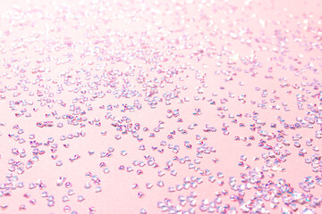 Tiny silver crystal confetti on a pink background. Selective focus. Glowing texture.