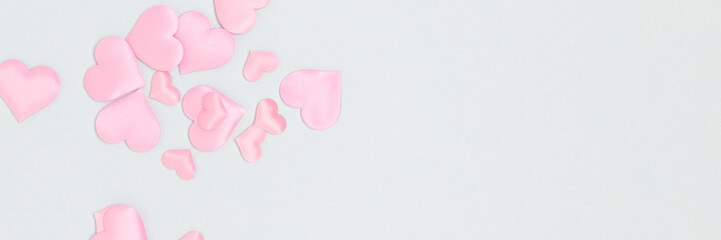 Banner with pink hearts confetti on a blue background. Concept with copy space.