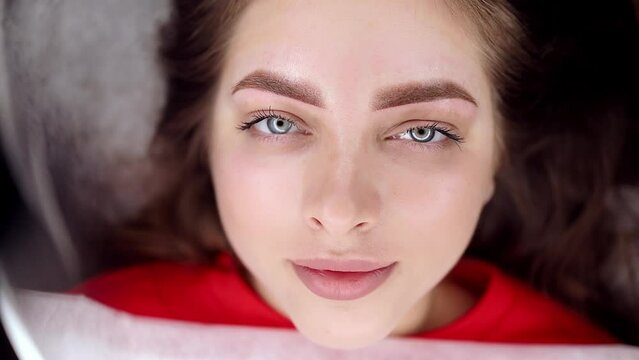 Chic girl model with performed permanent eyebrow makeup procedure she looks into the camera. Permanent makeup procedure, performing PMU of eyebrows
