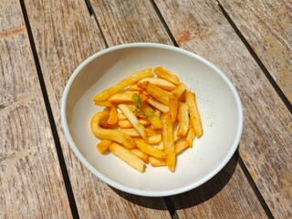 French fries on a white plate, and served on a wooden table