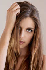 Fototapeta premium Portrait, straight hair and woman with makeup in salon treatment for care. Serious face, hairstyle shine and confident model in beauty cosmetics at hairdresser isolated on a brown studio background