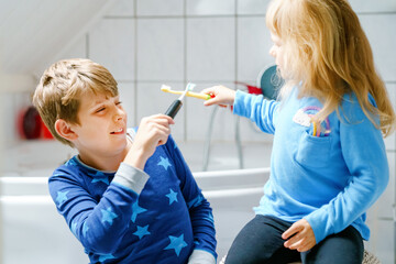 Little preschool girl and preteen school boy brushing teeth. Brother teaching sister brush teeth....