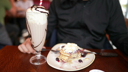 Man Enjoying Pancakes and Milkshake, Savoring Sugary Dessert at Restaurant