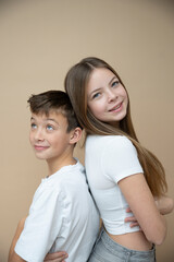 beautiful pretty 14 years old girl with her cute and cool 11 years old brother in front of brown background, brother and sister love