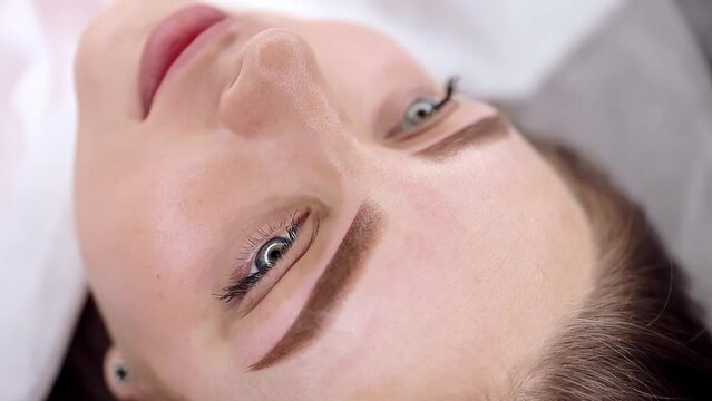 Beautiful girl with gorgeous permanent eyebrow makeup poses for the camera. Permanent makeup procedure, performing PMU of eyebrows