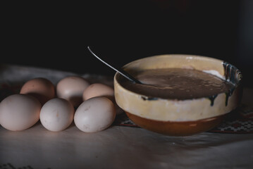 Growing yeast placed in a clay bowl next to organic farm eggs. Organic ingredients for cooking cakes at home