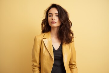 Fototapeta premium Portrait of a tender woman in her 20s sporting a stylish leather blazer against a pastel yellow background. AI Generation