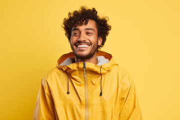 Fototapeta premium Portrait of a blissful indian man in his 20s wearing a lightweight packable anorak against a pastel yellow background. AI Generation