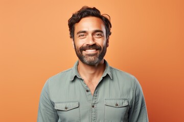 Fototapeta premium Portrait of a jovial man in his 30s sporting a versatile denim shirt against a pastel orange background. AI Generation