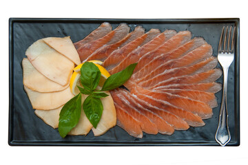 Fish platter with salmon slice and halibut, decorated with lemon and basil on a rectangular marble...