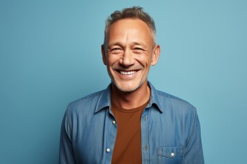 Fototapeta premium Portrait of a happy man in his 50s donning a trendy cropped top against a soft blue background. AI Generation
