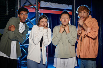 group of diverse and astonished young people looking at camera and discovering a clue in escape room