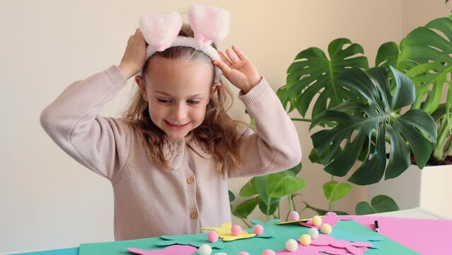 Happy toddler smile with teeth excited funny surprised child prepare for Easter party make paper garland colored Easter bunny DIY. Happy kids holidays. Girl wearing bunny ears costume