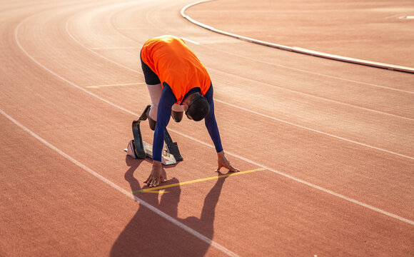 Asian para-athlete runner prosthetic leg on the track alone outside on a stadium track Paralympic running concept.
