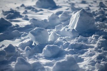 Heaps of snow and clumps that were piled up on the edge when clearing a path in winter in bright...