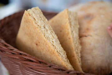Slices of fresh traditional corn bread in the shape of triangles, served in a wicker basket 