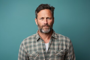 Obraz premium Portrait of a tender man in his 40s wearing a comfy flannel shirt against a soft teal background. AI Generation
