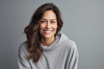 Fototapeta premium Portrait of a blissful woman in her 30s dressed in a comfy fleece pullover against a soft gray background. AI Generation