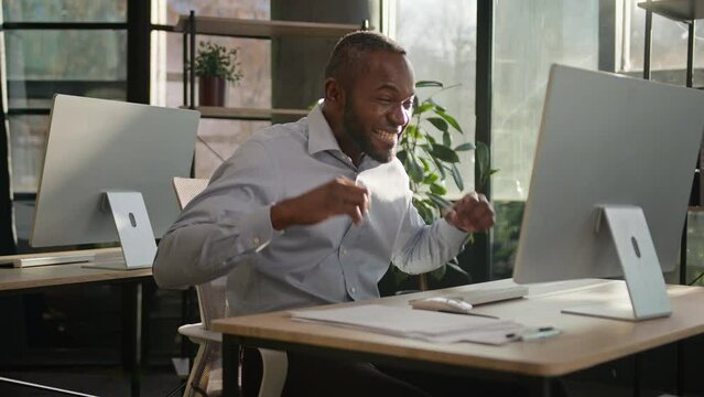 Business success African American ethnic man happy mature 40s middle-aged businessman employee in sunny office working online on computer win prize profit emotional celebrate winning victory triumph
