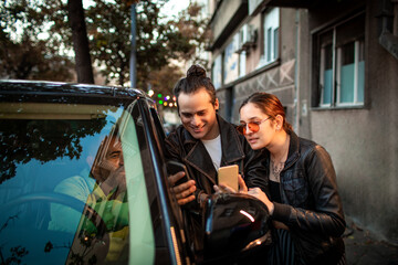 Young couple paying for rideshare with smartphone in city