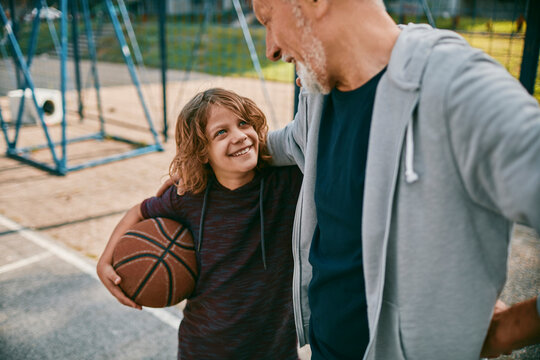 Grandfather and grandson bonding over basketball on outdoor court