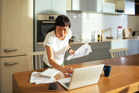 Young Asian woman paying bills online on a laptop at home