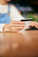 Close-up of a female hand holding a credit card, reading informations.