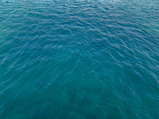 Blue green surface of the ocean with gentle ripples on the surface and light refracting. Natural background. The sea, the surface of the water. Close-up. Copy space