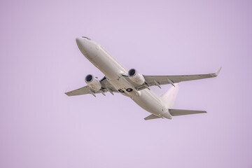 A passenger plane ascending in a homogeneous light purple sky