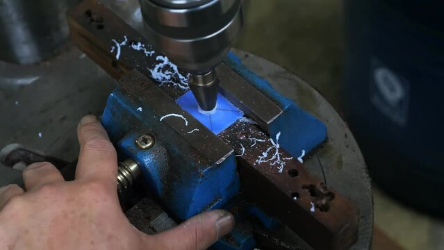 Process of making round holes in square workpieces made of plastic, brass, and wood using a special drilling machine.